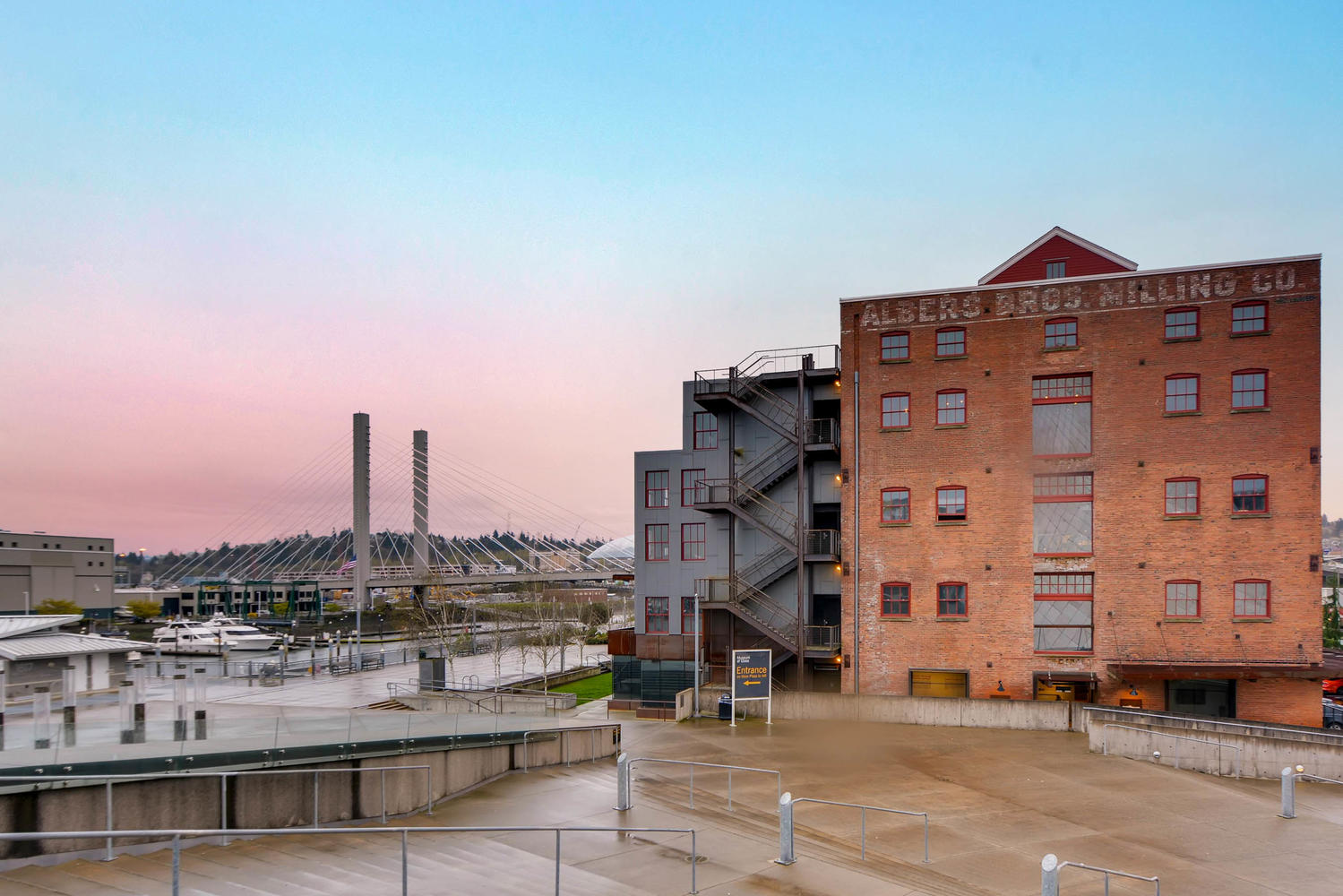 Exterior view of an old brick building with a bridge in the distance