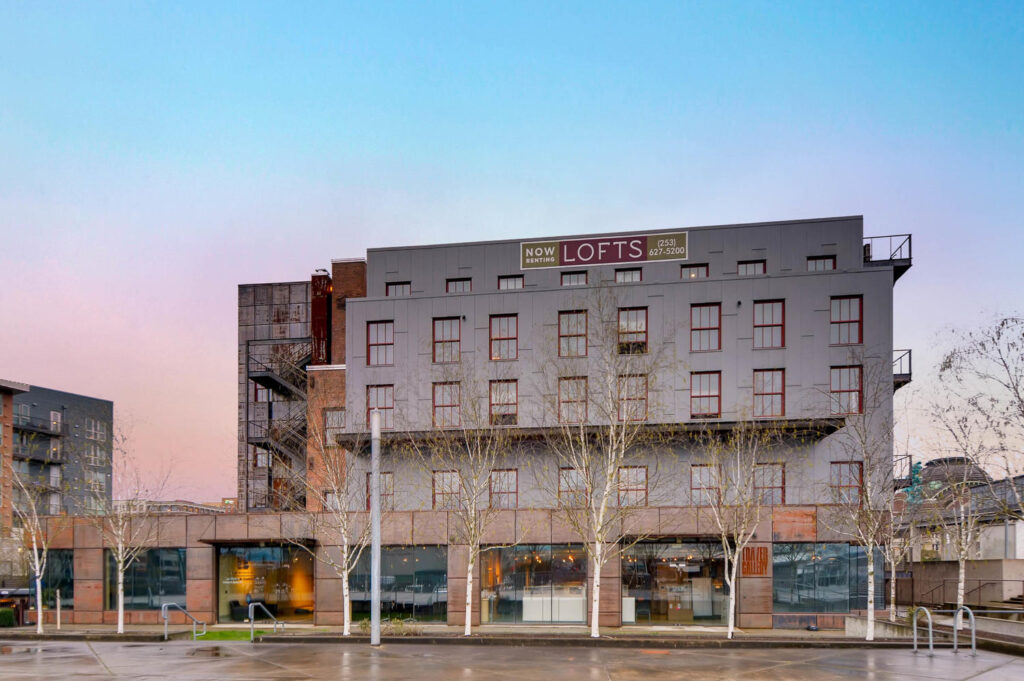 Building exterior with balconies, a banner that reads Now Renting Lofts 2 5 3 6 3 7 5 2 0 0
