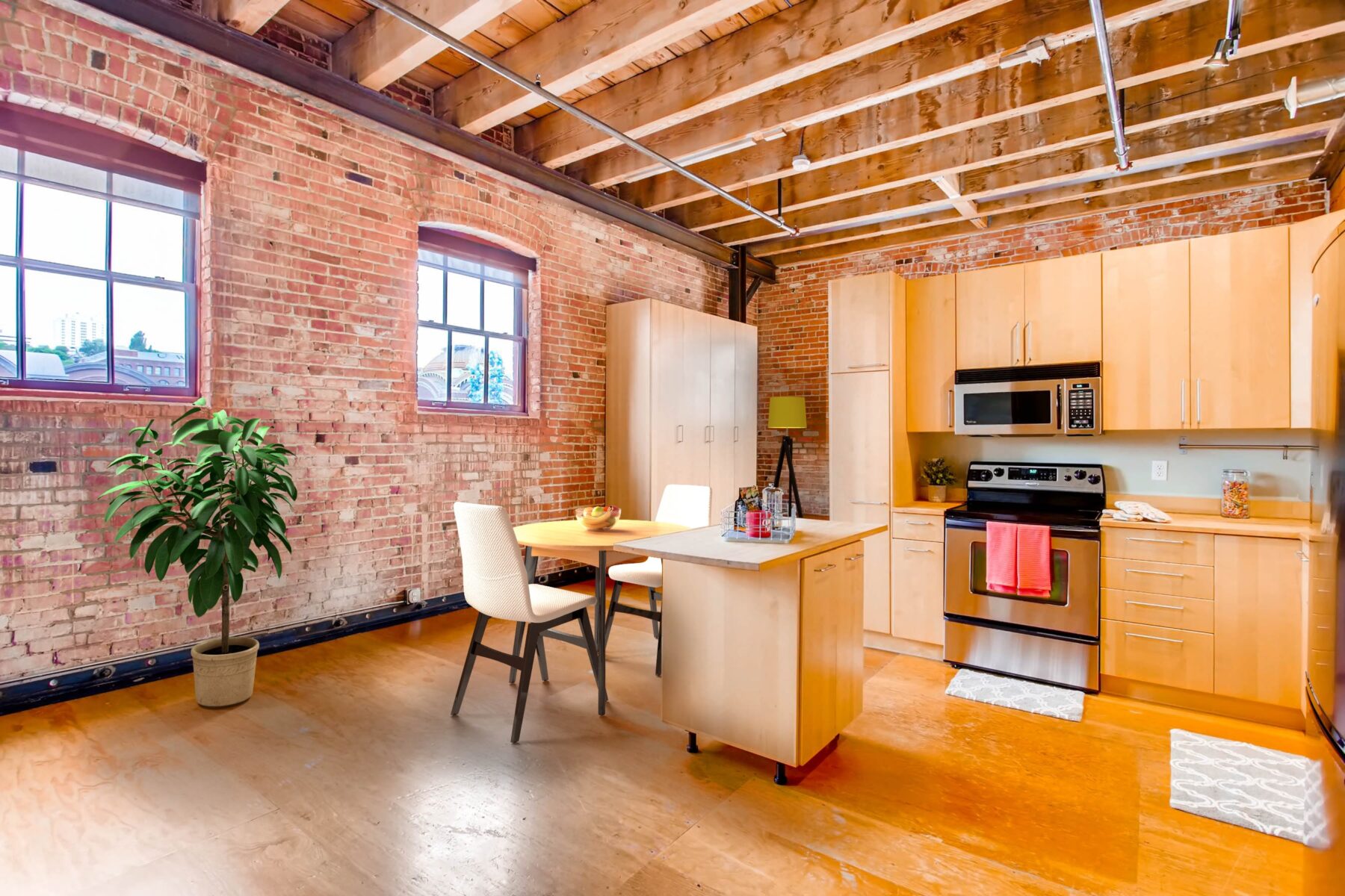 Open kitchen with wooden cabinets, stainless steel appliances, wooden flooring and dining area